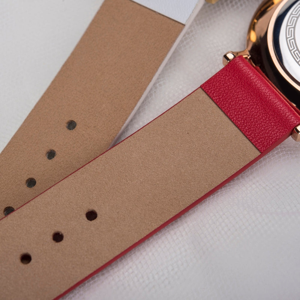 Close-up view of the underside of two wristwatch straps, one red and one white, showcasing a smooth, tan leather finish with multiple punch holes for adjustable fitting.