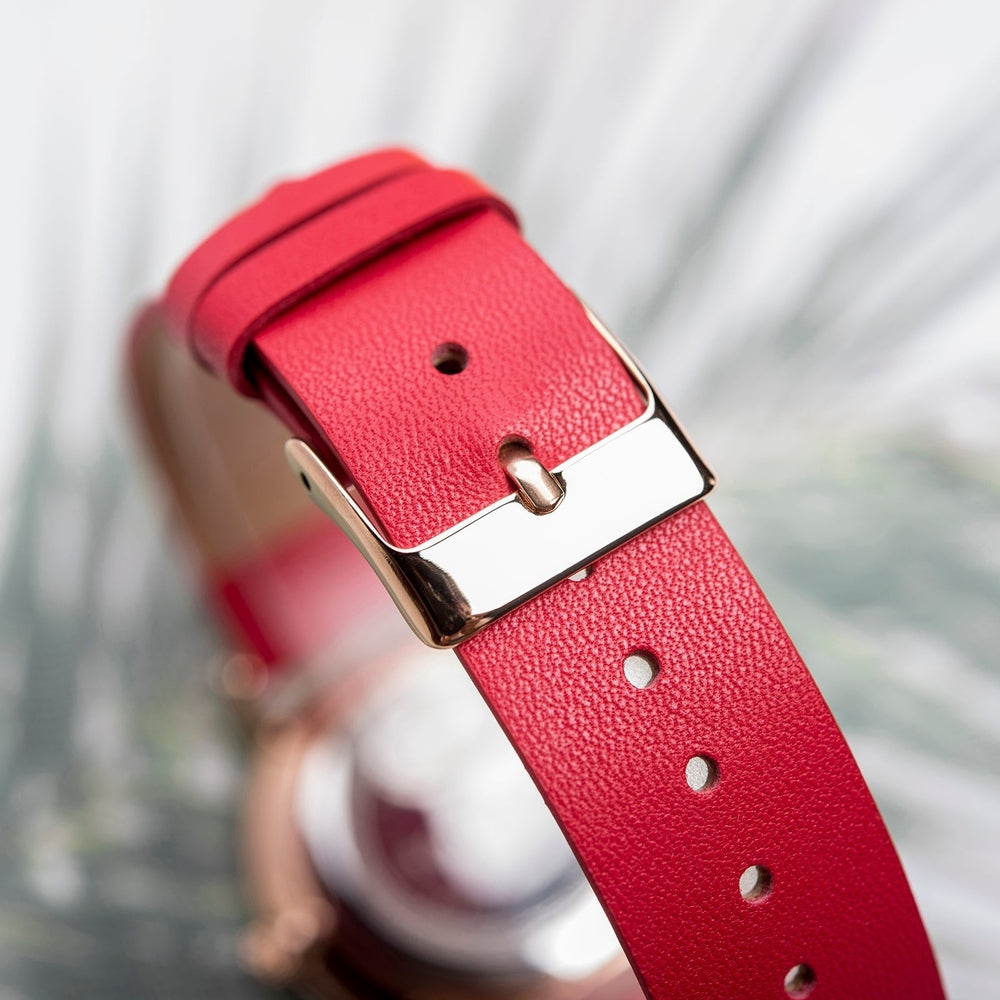 Detailed view of a red leather watch strap with a polished silver buckle, showcasing its high-quality craftsmanship and adjustable holes for a perfect fit.