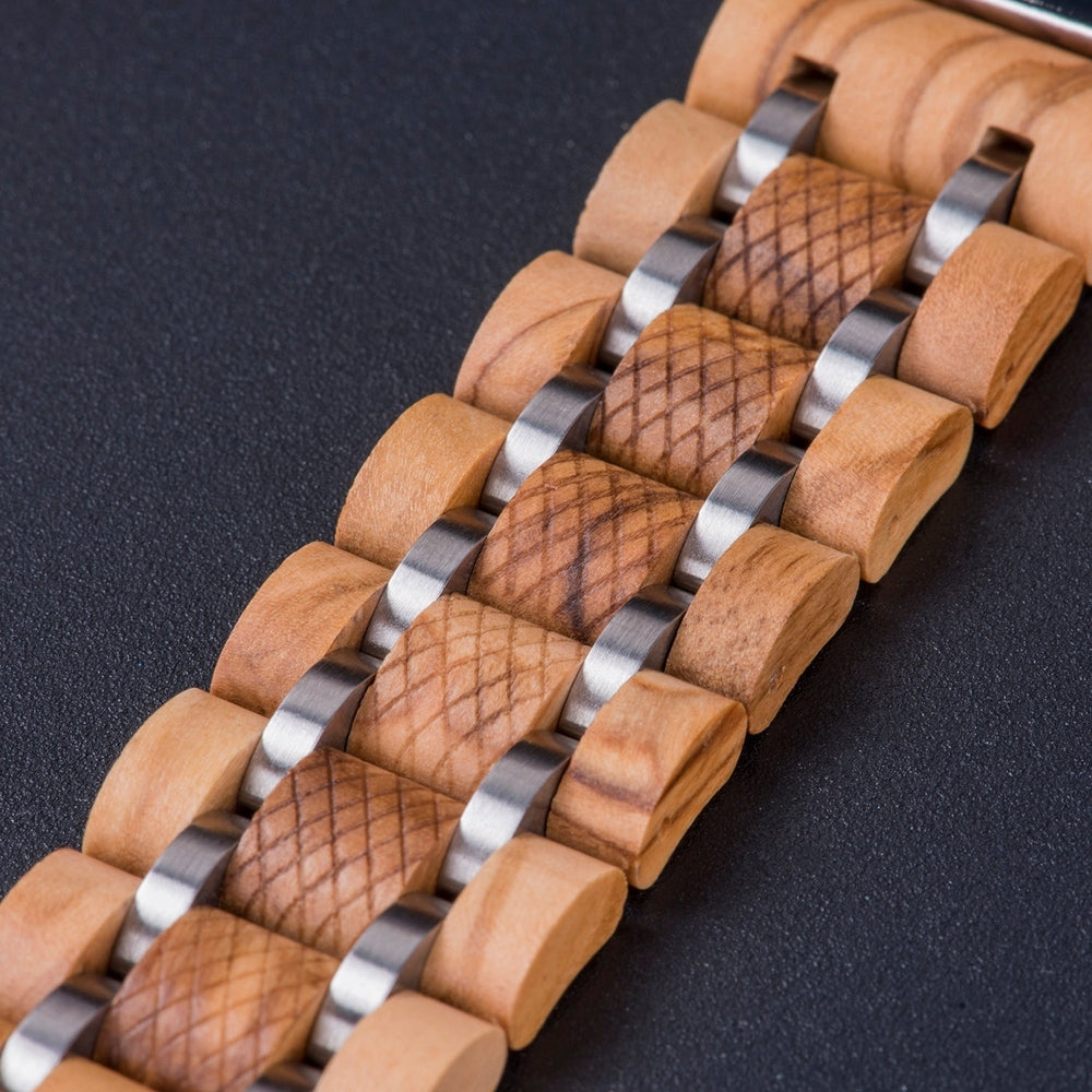 Close-up of a light wooden watch band with silver metal links and textured wood segments, showcasing intricate craftsmanship on a dark surface.