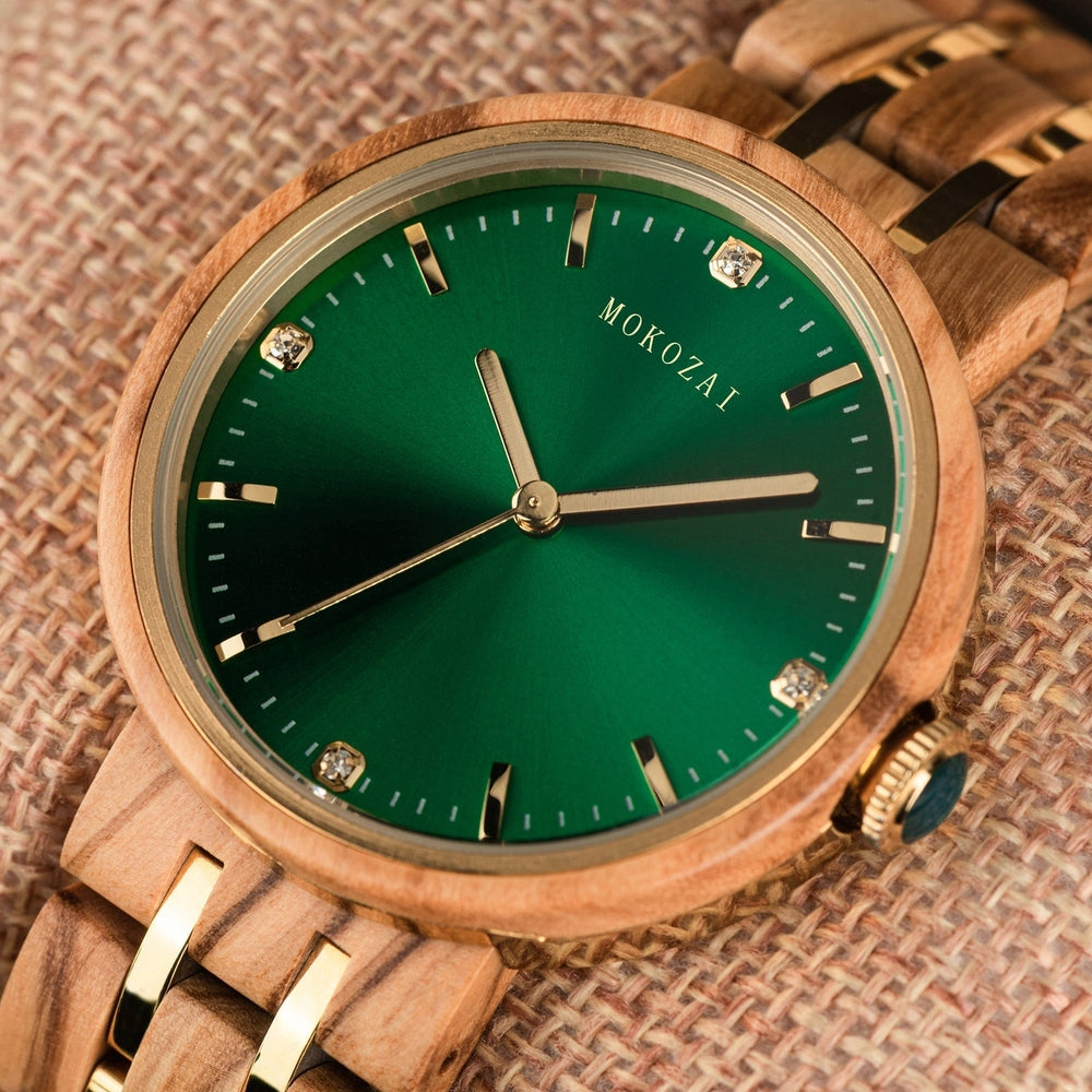 Close-up of a Mokozai wooden wristwatch with a vibrant green dial, golden hour markers, and delicate crystal details. The wooden bracelet and golden accents enhance the luxurious and natural aesthetic of the timepiece.