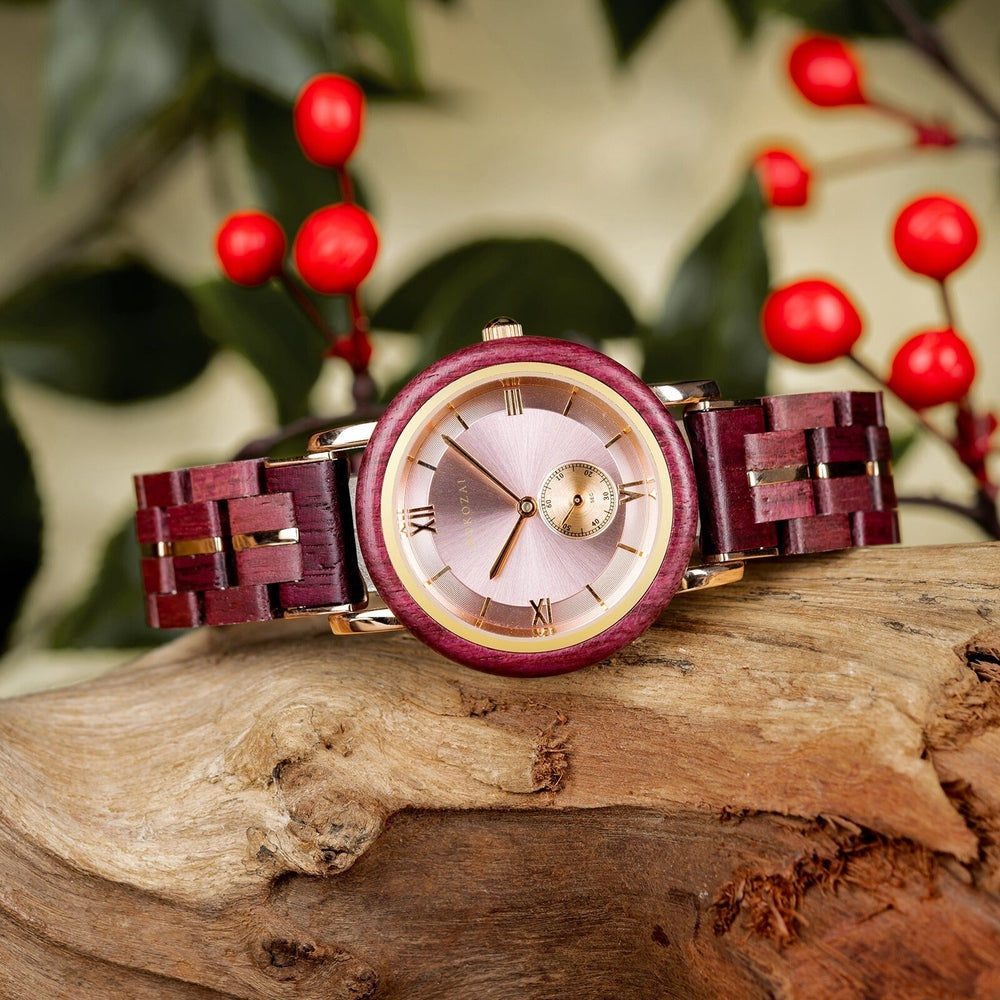 Elegant Mokozai women's watch with a deep purple wooden frame and strap, complemented by a rose gold case and a pink dial with Roman numerals. The eco-friendly wood construction pairs beautifully with the natural wood backdrop and red berries, making it a stylish, sustainable accessory for Australian shoppers seeking both luxury and environmental responsibility.