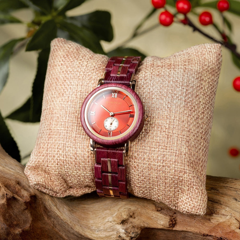 Elegant Mokozai red and gold wooden watch, featuring a deep red dial with Roman numerals, displayed on a textured cushion with festive red berries in the background. Perfect for Australians seeking luxurious, eco-friendly timepieces.