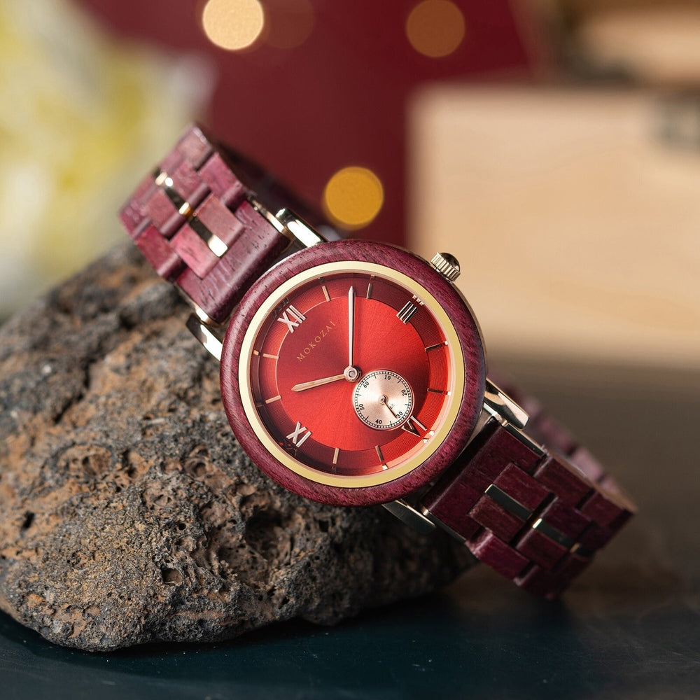 Luxurious Mokozai wooden watch with a striking red dial and matching red and gold strap, elegantly resting on a textured rock. Roman numerals and a subdial add sophistication, perfect for eco-conscious Australians seeking a blend of natural beauty and luxury.
