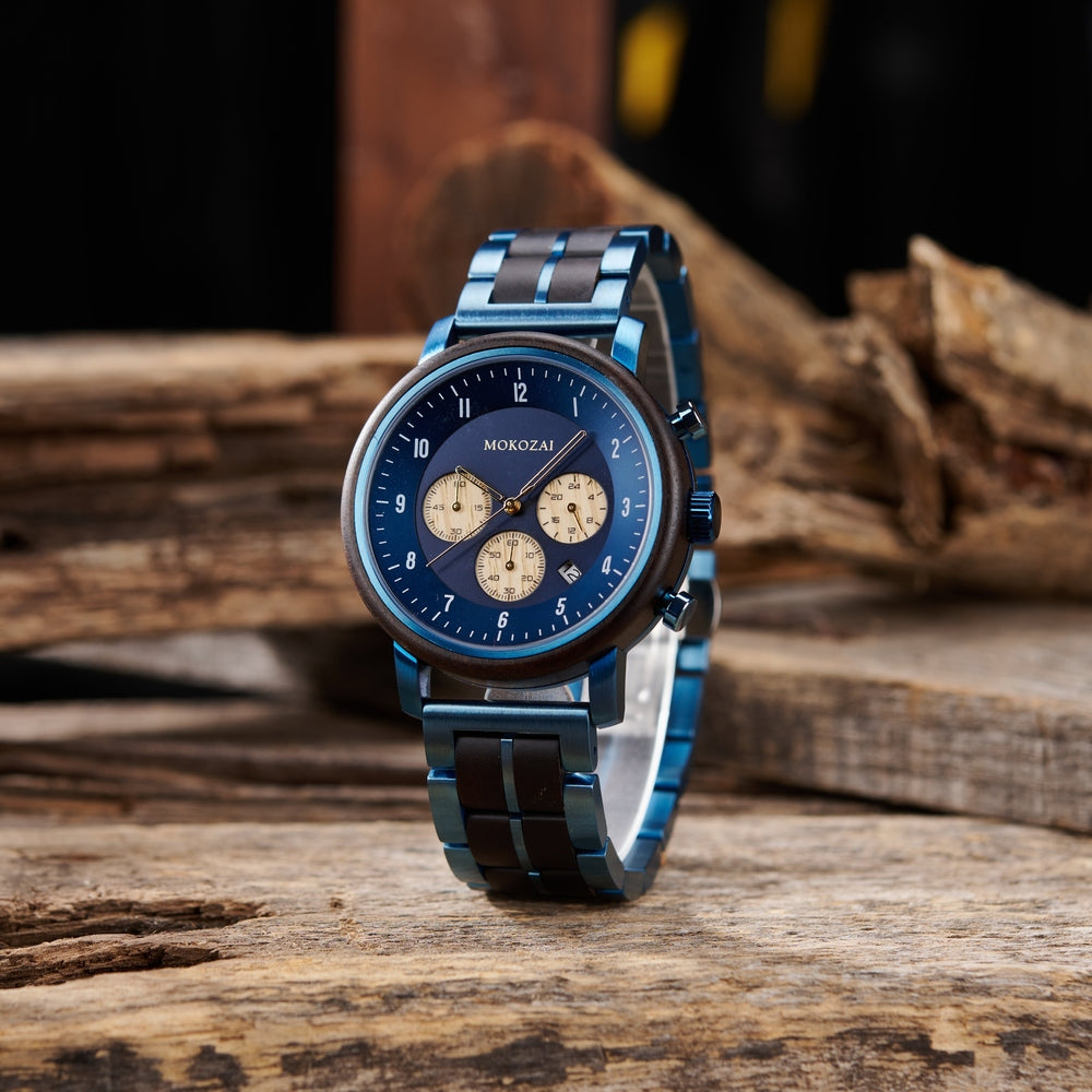Front view of Mokozai men's chronograph watch with a blue dial and cream sub-dials, set against a rustic wooden background. The watch features a sleek blue and black wood-accented strap, highlighting the brand's nature-inspired luxury design.