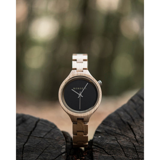 Minimalist wooden wristwatch with a black dial and light woodgrain band, showcased on a natural tree stump background. The simple design highlights Mokozai's eco-friendly luxury craftsmanship. Perfect for nature-loving, style-conscious individuals in Australia.