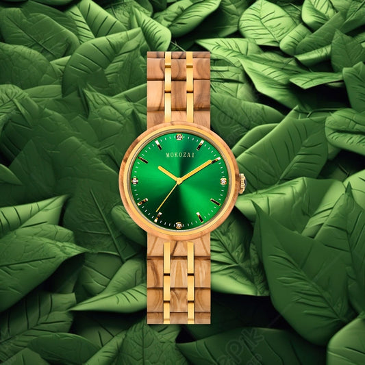 Mokozai wristwatch featuring a striking emerald green dial with gold-tone hands and markers, set in a light wooden case and matching wooden bracelet with gold accents. The watch is displayed against a backdrop of lush green leaves, emphasizing its natural and luxurious design.